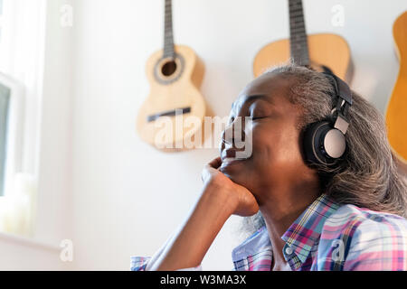 Reife Frau, die Musik über Kopfhörer hören Stockfoto
