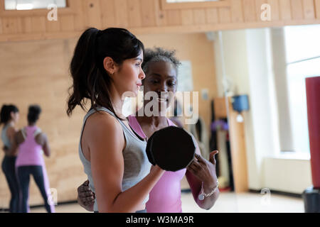 Frau mit Personal Trainer, Gewichte zu heben in der Turnhalle Stockfoto