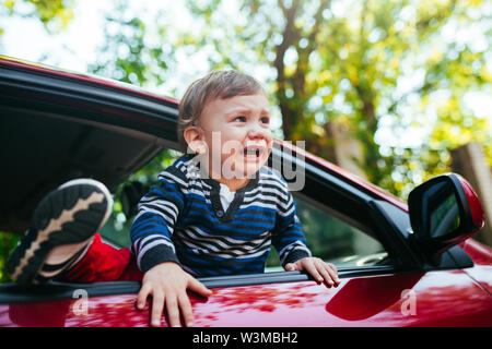 Schreiendes baby boy im Auto. Der Junge schreit und will aus dem maniche zu erhalten Stockfoto