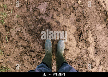 Er schmutzig Landwirt Gummistiefel auf matschigen Landstraße. Agronom ist zu Fuß den Weg durch die Felder nach starkem Regen Sturm. Stockfoto