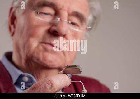 Der ältere Mann mit Hörgerät Stockfoto