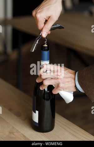 Die Hände des Menschen öffnen Flasche Wein Stockfoto