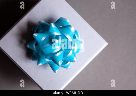Geschenkbox mit blauer Schleife auf dunkelgrauem Hintergrund. Flach. Festliche Konzept. Stockfoto