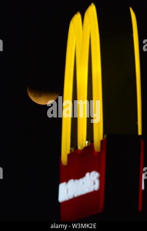 Glasgow, UK. 16. Jul 2019. Mond Mack. Es liebevoll von der McDonalds Drive Thru, die partielle Mondfinsternis von Wolken am Himmel in Glasgow gesehen. Credit: Colin Fisher/Alamy leben Nachrichten Stockfoto