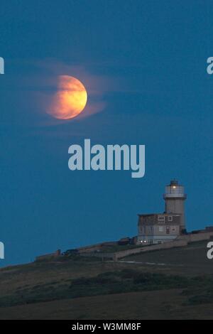 Beachy Head, UK. 16. Jul 2019. UK Wetter. Heute Abend voller Mond partielle Sonnenfinsternis steigt hinter Belle Tout Lighthouse in East Sussex, UK. Credit: Ed Brown/Alamy leben Nachrichten Stockfoto