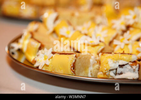 Schöne Stücke von gelben Pound Cake iced mit gelben und weißen Blumen Stockfoto