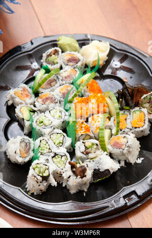 Lecker aussehenden California Rolls und andere Sorten von Sushi auf einer Plastikschale Stockfoto