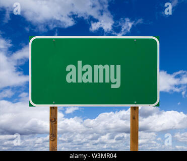 Leeren grünen Schild mit Holz- Beiträge über blauen Himmel und Wolken Stockfoto