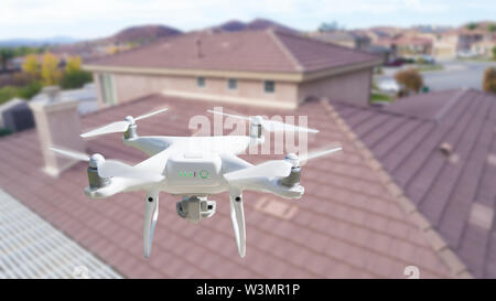 Unbemannte Luftfahrzeuge (UAV) Quadcopter Drohne in der Luft über Haus Inspektion des Daches. Stockfoto