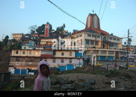 Ein Naga Kind mit der Mekokchung Stadt im Hintergrund, am Morgen. Nagaland, ist eine kleine hügelige Zustand, im nordöstlichen Teil von Indien. Die Bevölkerung, (zumeist ethnischen Naga) ist fast zwei Millionen. Es hat eine Fläche von 6,401 Quadratkilometern und ist damit einer der kleinsten Staaten Indiens. Als 90.02% der Bevölkerung sind Christen, die Hill State ist als die am meisten besiedelte Baptist, in der ganzen Welt bekannt. 31. Dezember 2008. Stockfoto