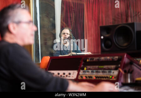 10 Juli 2019, Hessen, Frankfurt/Main: Heiko Grauel (r), professioneller Sprecher, schaut aus Stand seines Sprecher bei Stephan Becker, Sound Engineer' Spaß De Geistigen". Die neue Stimme für die Ansagen in Deutscher Stationen wurde bei einem Casting ausgewählt. Grauel's Stimme war für 60 Stunden aufgezeichnet. Bald wird es an alle die Deutsche Bahn Stationen zu hören. Foto: Andreas Arnold/dpa Stockfoto