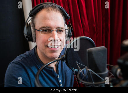 10 Juli 2019, Hessen, Frankfurt/Main: Heiko Grauel spricht in der Aufnahme das Mikrofon. Heiko Grauel wurde bei einem Casting als neue Stimme für die Ansagen in deutschen Bahnhöfen ausgewählt. Grauel's Stimme war für 60 Stunden aufgezeichnet. Bald wird es an alle die Deutsche Bahn Stationen zu hören. Foto: Andreas Arnold/dpa Stockfoto