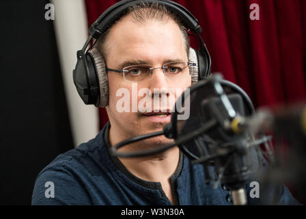 10 Juli 2019, Hessen, Frankfurt/Main: Heiko Grauel spricht in der Aufnahme das Mikrofon. Heiko Grauel wurde bei einem Casting als neue Stimme für die Ansagen in deutschen Bahnhöfen ausgewählt. Grauel's Stimme war für 60 Stunden aufgezeichnet. Bald wird es an alle die Deutsche Bahn Stationen zu hören. Foto: Andreas Arnold/dpa Stockfoto