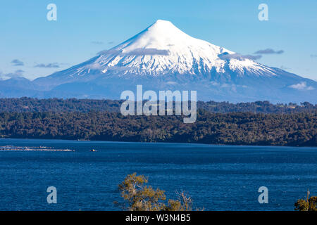 Die erstaunliche schneebedeckten Vulkan Osorno Gipfel über dem Wasser und Wolken von Rupanco See, die Bäume im Wald und die Wolken ein beeindruckender Landschaft Stockfoto