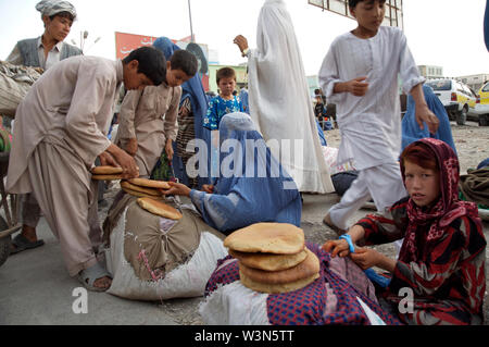 Die afghanischen Frauen und Kinder verkaufen gebackenes Brot, am Hauptmarkt von Mazar-e-Sharif, in der nördlichen Provinz Balkh. Schätzungsweise 60.000 Kinder, zerbrochene Familien, Armut und Konflikten flohen, und jetzt leben oder arbeiten in den Straßen der großen Städte. Afghanistan. 26. Juni 2007. Stockfoto