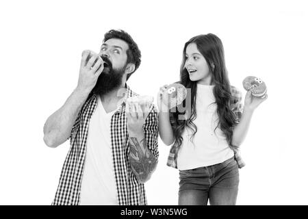 Wir haben Leidenschaft für leckere Donuts. Vater und kleine Tochter essen glasierte Krapfen. Mann und Mädchen Kind holding Ring Donuts Bärtigen. Hipster und cute kid mit gebratenen Donuts in den Händen. Stockfoto