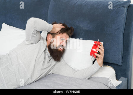 Morgen erwachen. Mann wach unzufrieden mit Wecker klingeln. Obwohl sie schlafen können, wie überhaupt nicht schlafen. Phasen des Schlafes. Auf verpassten Schlaf nachholen während des Wochenendes. Stockfoto