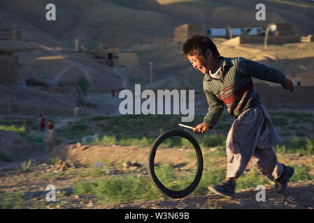 Eine lachende Junge jagt ein Fahrrad Schlauch mit einem Stock, in der Ortschaft Ragshad, am Stadtrand von Bamian Stadt in der zentralen Provinz Bamyan. Er ist Mitglied der ethnischen Minderheit der Hazara. Im Juni 2007 in Afghanistan, chronischer Unsicherheit und neuer Gewalt, vor allem in ländlichen Gebieten, weiterhin die Wiederherstellung nach Jahrzehnten des Krieges zu behindern, und beschränken Sie den Fortschritt für alle 25 Millionen Menschen des Landes - insbesondere der Frauen und Kinder. Soziale Indikatoren der Nation Rang oder nahe an der Unterseite unter den Entwicklungsländern: die durchschnittliche Lebenserwartung liegt unter 45 Jahren; 40 bis 60 Prozent der afghanischen Kind Stockfoto