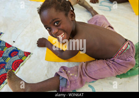 Sitzen auf dem Boden, ein junges Mädchen in Côte d'Ivoire, die sich in Liberia mit ihrer Familie genommen hat, lächelt, während Sie zeichnen Bilder in einer kinderfreundlichen Raum (CFS) ausführen, indem Sie die Kinder im Dorf Neue Pohan der Tchin Bezirk im Grand Gedeh County. Liberia. 2012, Liberia ist noch Erholen von einem ruinösen 14-jährigen Bürgerkrieg, der 2003 endete. Obwohl die Regierung arbeitet zerstörte Infrastruktur des Landes wiederaufzubauen, viele Liberianer weiter ohne Zugang zu grundlegenden Dienstleistungen zu leben. Der Zustrom von rund 178.000 Flüchtlinge aus Côte d'Ivoire, die ihr eigenes Land geflohen Ein Stockfoto