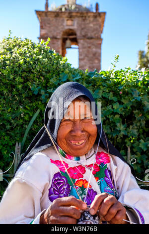 Porträt der älteren indigenen Quechua Senior Frau in traditionellen peruanischen Kleidung, Stricken, Lächeln, Amantani Insel, Titicaca-See, Peru Stockfoto