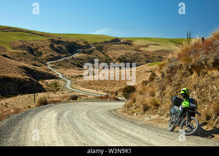 Abenteuer Motorrad und Straße durch tussocks, in der Nähe der See Mahinerangi, Otago, Südinsel, Neuseeland Stockfoto