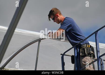 Greymouth, Neuseeland, 12. Dezember 2018: Handwerker sichern Sie den Kunststoff auf einen neuen Tunnel House. Stockfoto