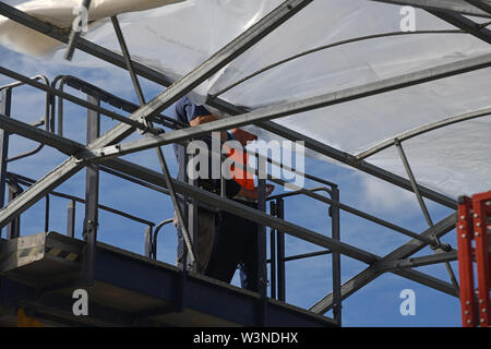 Greymouth, Neuseeland, 12. Dezember 2018: Handwerker sichern Sie den Kunststoff auf einen neuen Tunnel House. Stockfoto