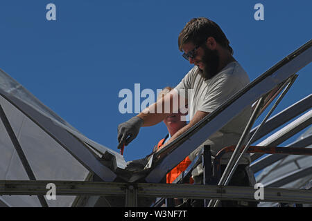 Greymouth, Neuseeland, 12. Dezember 2018: Handwerker sichern Sie den Kunststoff auf einen neuen Tunnel House. Stockfoto