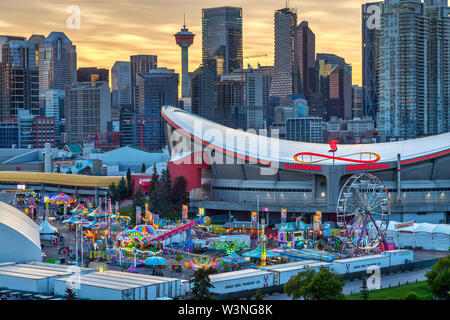 CALGARY, Kanada - 14. JULI 2019: Sonnenuntergang über Calgary Skyline mit dem jährlichen Ansturm bei den Saddledome. Das Calgary Stampede ist Curetis AG erhöht S... Stockfoto