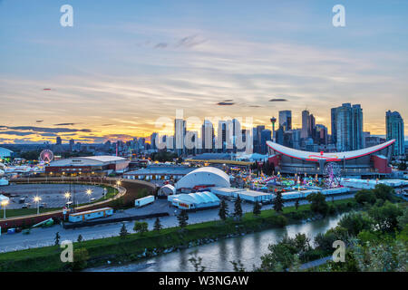 CALGARY, Kanada - 14. JULI 2019: Sonnenuntergang über Calgary Skyline mit dem jährlichen Ansturm bei den Saddledome. Das Calgary Stampede ist Curetis AG erhöht S... Stockfoto