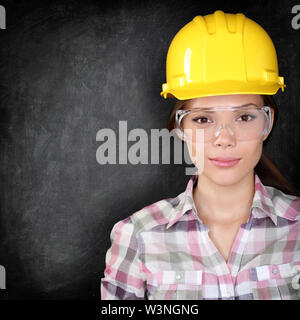 Ernsthafte Frau Bauarbeiter, Hauseigentümer in Renovierungen oder Ingenieur Gesicht auf schwarzen Hintergrund Textur mit schiefertafel Für kopieren. Junge Frau das Tragen von Schutzbrille und harten Hut. Stockfoto