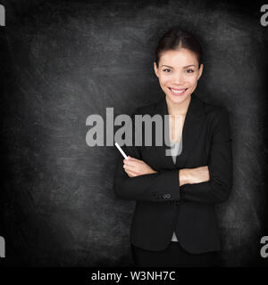 Frau Lehrerin oder Business Frau an der Tafel mit Kreide in Suit von blackboard Unterricht oder Vortrag. Junge weibliche Professionelle portrait. Gemischte Rasse asiatischen Kaukasischen weibliche Modell. Stockfoto