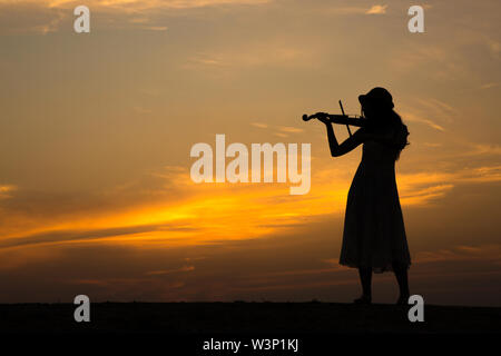 Silhouette der asiatischen Frau spielen Geige auf Sonnenuntergang Stockfoto