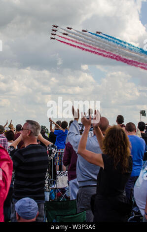 Royal Air Force Red Arrows display Team über die Menge an RAF Waddington Airshow anzuzeigen. Die Leute klatschen. Patriotische britische Team Stockfoto