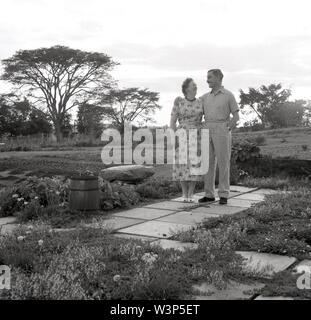 1950, historische, Ältere britisches Paar ständigen zusammen außerhalb ihrer Eigenschaft, Uganda. Das afrikanische Land war ein britisches Protektorat von 1894 bis 1962 und nach dem Zweiten Weltkrieg 11 Viele ex-Offiziere in der Armee war es, ein neues Leben zu beginnen, vor allem in der Landwirtschaft des Landes. Stockfoto