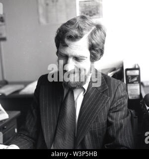 1970 s, historischen, einen bärtigen Mann in einem Büro in Anzug der Ära, ein Nadelstreifen mit breitem Revers und ein T-Shirt und "Kipper" binden. Stockfoto