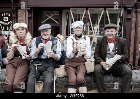 Die Menschen gekleidet in 1940s style Kleidung essen Fisch und Chips, Großbritannien Stockfoto