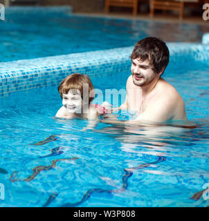 Ein Vater lehrt sein Kind, in einem Teich zu schwimmen. Ertrinken ist
