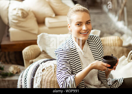 Nachdenklich gut aussehende Frau. Ansprechende positive Frau mit blonden Haaren gebunden ruht auf einem Sofa, während Sie Pause in ruhiger Umgebung Stockfoto