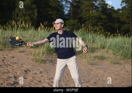 Mann spielt Beach Tennis in Sanddünen Stockfoto