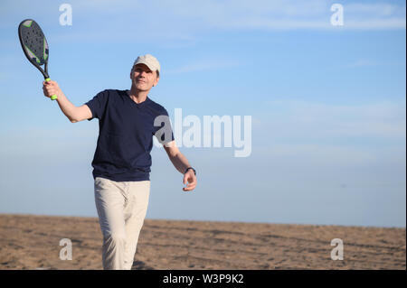 Mann spielt Beach Tennis auf einem sandigen Strand Stockfoto