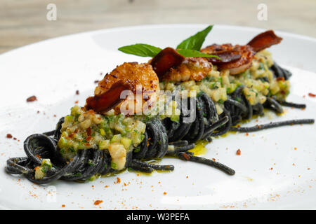Nahaufnahme der tagliolini squid Tinte schwarz pasta Jakobsmuschel fisch Sauce, bottarga roe Meeräsche Eier, Zucchini Gemüse frische Sahne, Knoblauch, Basilikum, italienische f Stockfoto