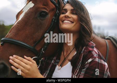 Der glückliche junge Frau umarmte ihre Pferd. Cowgirl lieben ihr Pferd im Freien. Stockfoto
