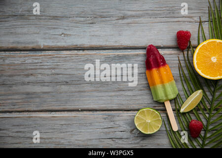 Sommer Eis am Stiel mit Obst und eine tropische palm leaf auf einer hölzernen Hintergrund Stockfoto