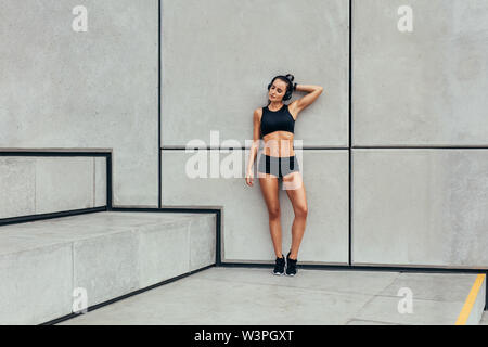 Frau ausruhen nach Training. Die ganze Länge der sportliche junge Frau entspannend nach dem Ausführen der Übung. Stockfoto