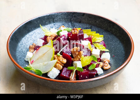 Nahaufnahme der frische, gesunde Rote-Bete-Salat mit Feta Käse, in Scheiben geschnittenen Äpfel, Walnüsse, sprießen garnieren Italienisch professioneller Koch Restaurant Speisen und Pla Stockfoto