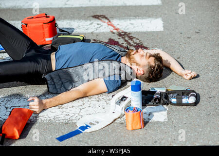 Verletzte blutender Mann liegen auf dem Fußgängerüberweg in der Notfallversorgung nach dem Verkehrsunfall Stockfoto