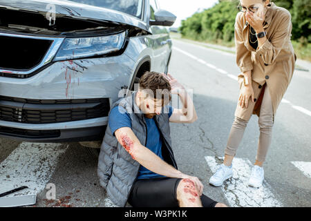 Frau Treiber Gefühl es tut uns Leid über verletzte Mann Leiden auf dem Fußgängerüberweg in der Nähe des Auto nach dem Unfall Stockfoto