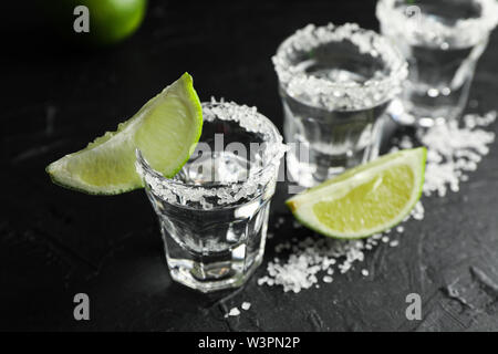 Tequila Schüsse mit Salz und Limette Schichten auf schwarzem Hintergrund Stockfoto