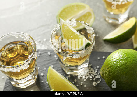 Tequila Schüsse mit Salz und Limette Schichten auf grauem Hintergrund Stockfoto